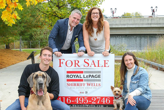 The Shirriff Wells team with a For Sale sign and pet dogs.